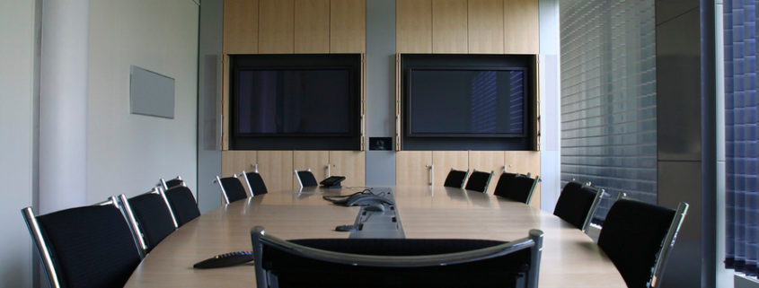 Conference room with two mounted displays and omnidirectional mic.