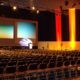 conference room with stage, show-style lighting and chairs for attendees