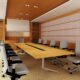 Empty conference room with a projector screen, chairs are slightly pulled out from underneath a long table