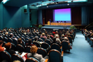 a large hall filled with people sitting on chairs