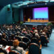 a large hall filled with people sitting on chairs