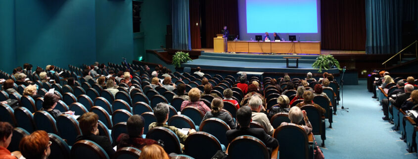 a large hall filled with people sitting on chairs