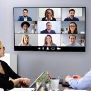 Employees in a small conference room on a video call.