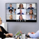 Employees in a small conference room on a video call.