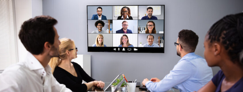 Employees in a small conference room on a video call.