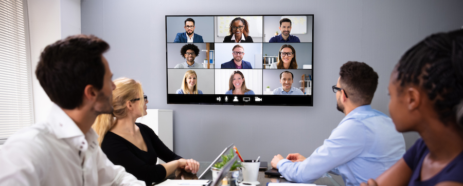 Employees in a small conference room on a video call.