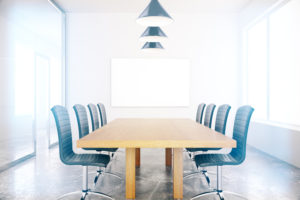 Well lit conference room with six blue chairs and a white board.