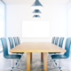 Well lit conference room with six blue chairs and a white board.