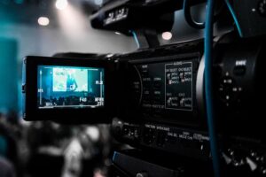 A professional video camera displaying a person on the screen.