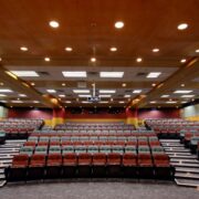 A large room designed for presentations. A projector hangs from the ceiling.