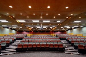 A large room designed for presentations. A projector hangs from the ceiling.