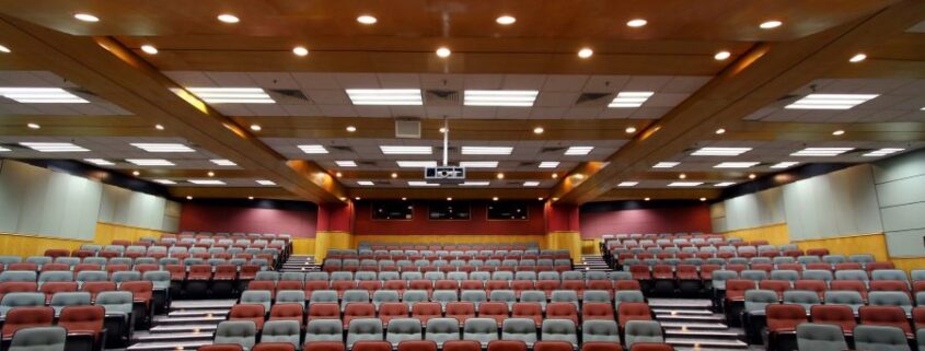 A large room designed for presentations. A projector hangs from the ceiling.
