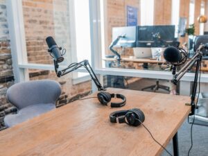 A recording studio featuring two microphones and a pair of headphones on a table. 