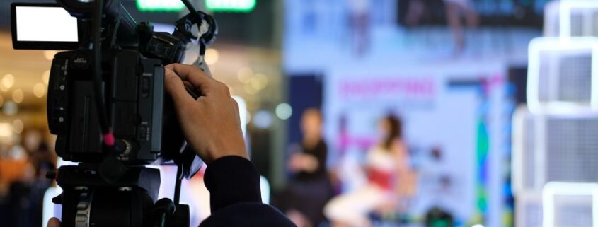 The hands of an AV technician on camera equipment focused on an event happening in the distance.