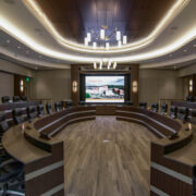 UT Medical collaboration room with large conference table and plush chairs in front of a display screen