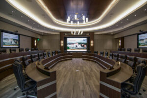 UT Medical collaboration room with large conference table and plush chairs in front of a display screen