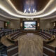 UT Medical collaboration room with large conference table and plush chairs in front of a display screen