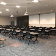 corporate training room with rows of tables, two projectors, and two projection screens