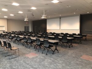 corporate training room with rows of tables, two projectors, and two projection screens