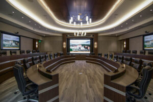A large boardroom with many seats, a large screen, microphones, and speakers managed by remote monitoring services.
