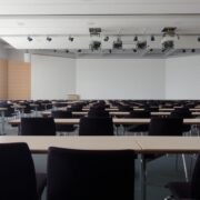 Large classroom with neatly arranged tables and chairs, equipped with overhead lighting and projection systems.