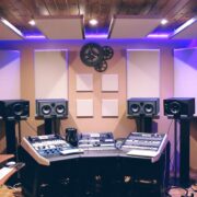 A modern recording studio illuminated by purple LED lights.