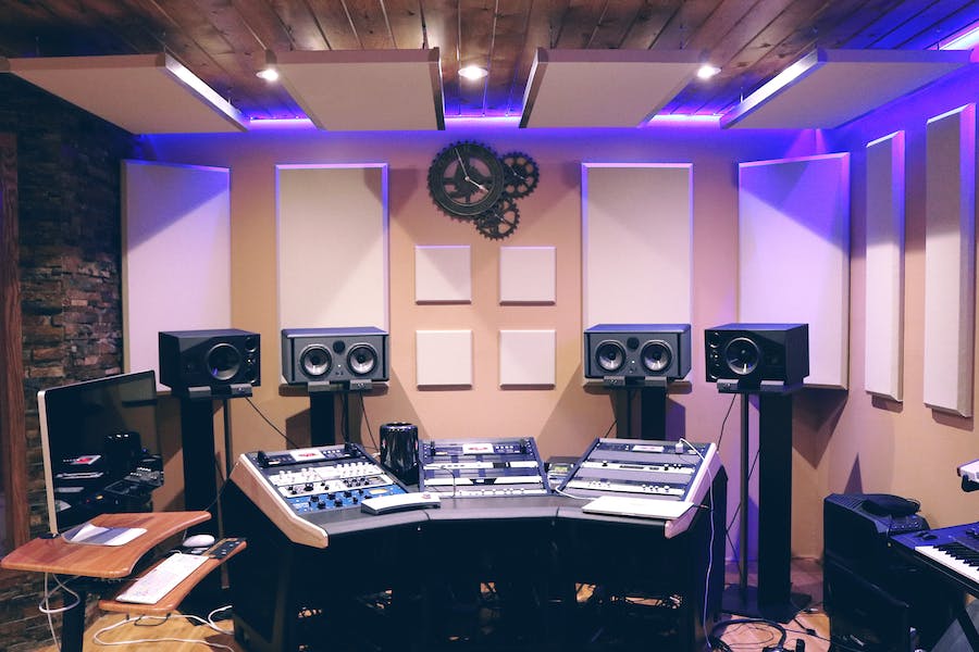 A modern recording studio illuminated by purple LED lights.