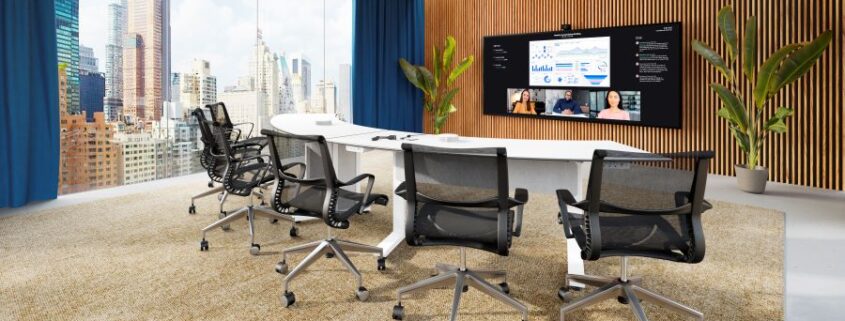 A modern conference room with a large display and skyscrapers in the distance.