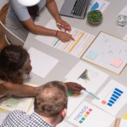 People gathered at a collaboration space with papers and laptops on the table.