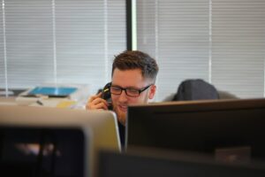 A man providing support services on the phone sitting in front of a computer.