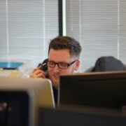 A man providing support services on the phone sitting in front of a computer.