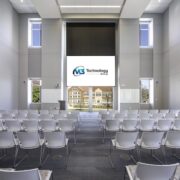 Auditorium-style event space with rows of chairs and a large projection screen displaying the M3 Technology Group logo.