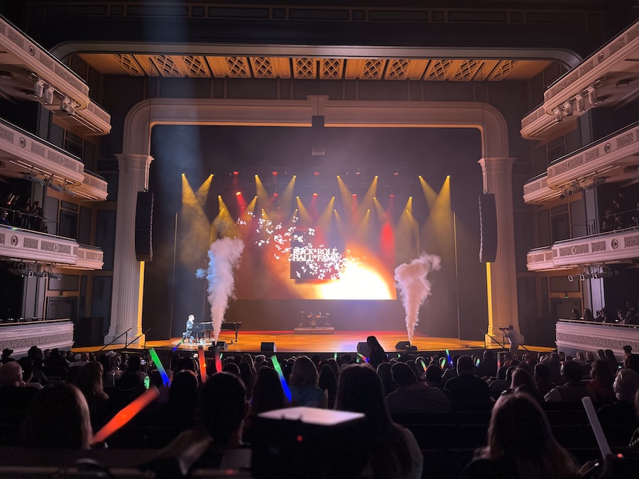 Live event stage with colorful red and yellow lights, theater seating in rows and balconies.