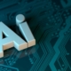 3D AI letters in light blue and tan resting atop a glowing teal circuit board pattern.